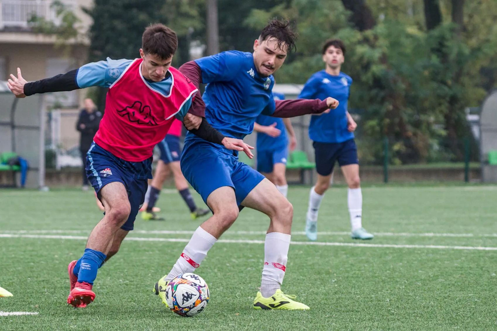 Dva nogometaša se natječu za loptu na zelenom terenu tijekom utakmice.
