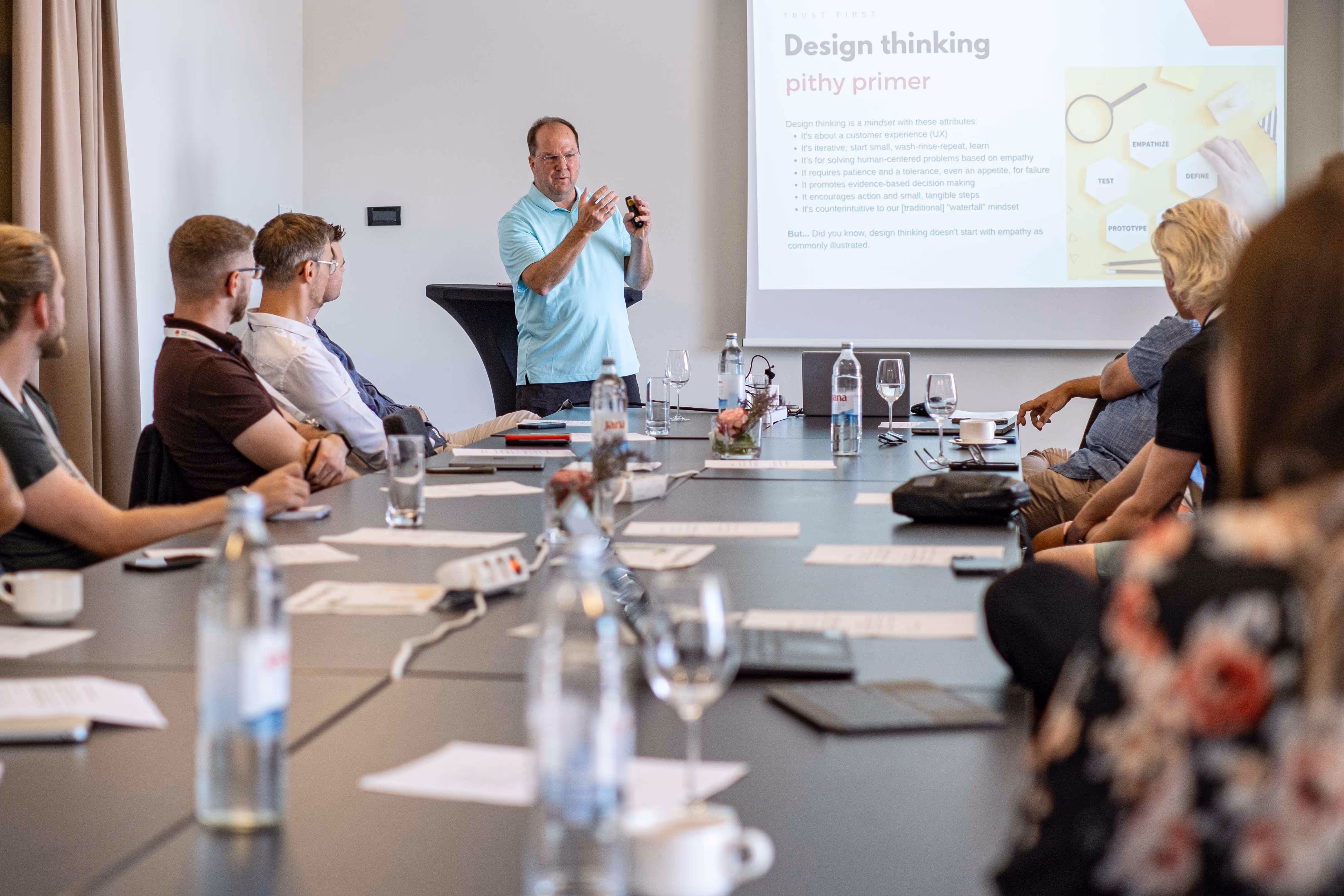 Predavač na konferenciji za stolom objašnjava o temi Design thinking.